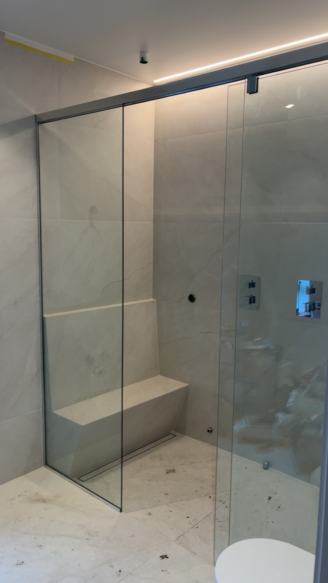 Nisjeløsning med skyvedør. 2 stk fastfelt med dør sentrert, fingerhull åpning. Løsningen er levert med Pilkington Optishower glass for enkelt renhold.
